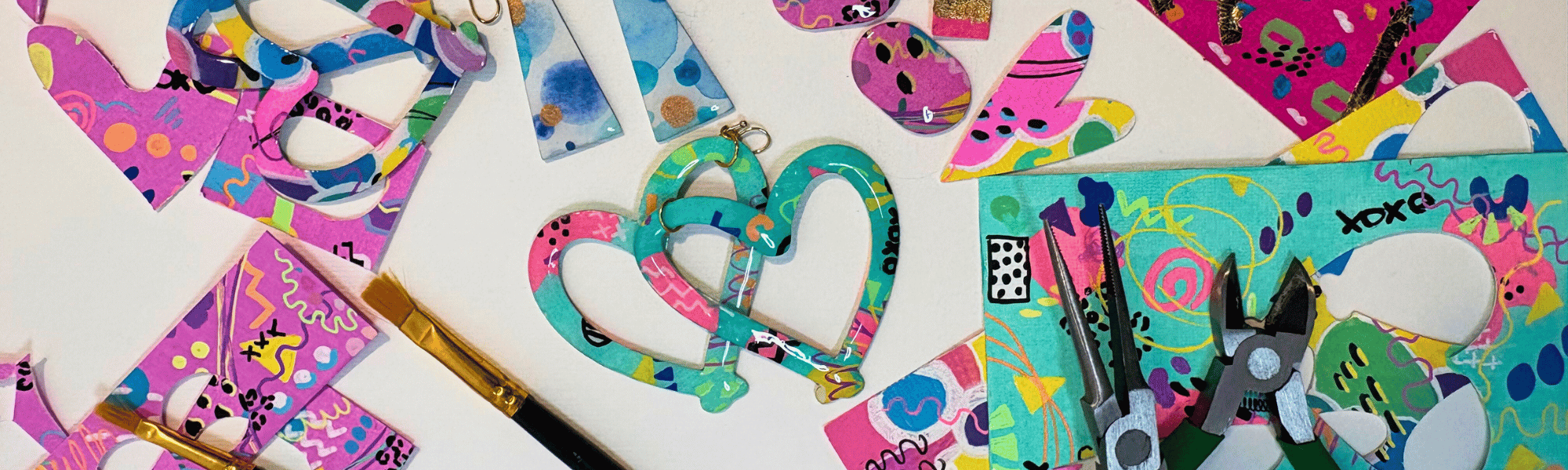 Colourful paper earrings and painted paper scraps on a white background